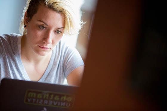 Photo of a student working on a laptop with a Chatham University sticker on it