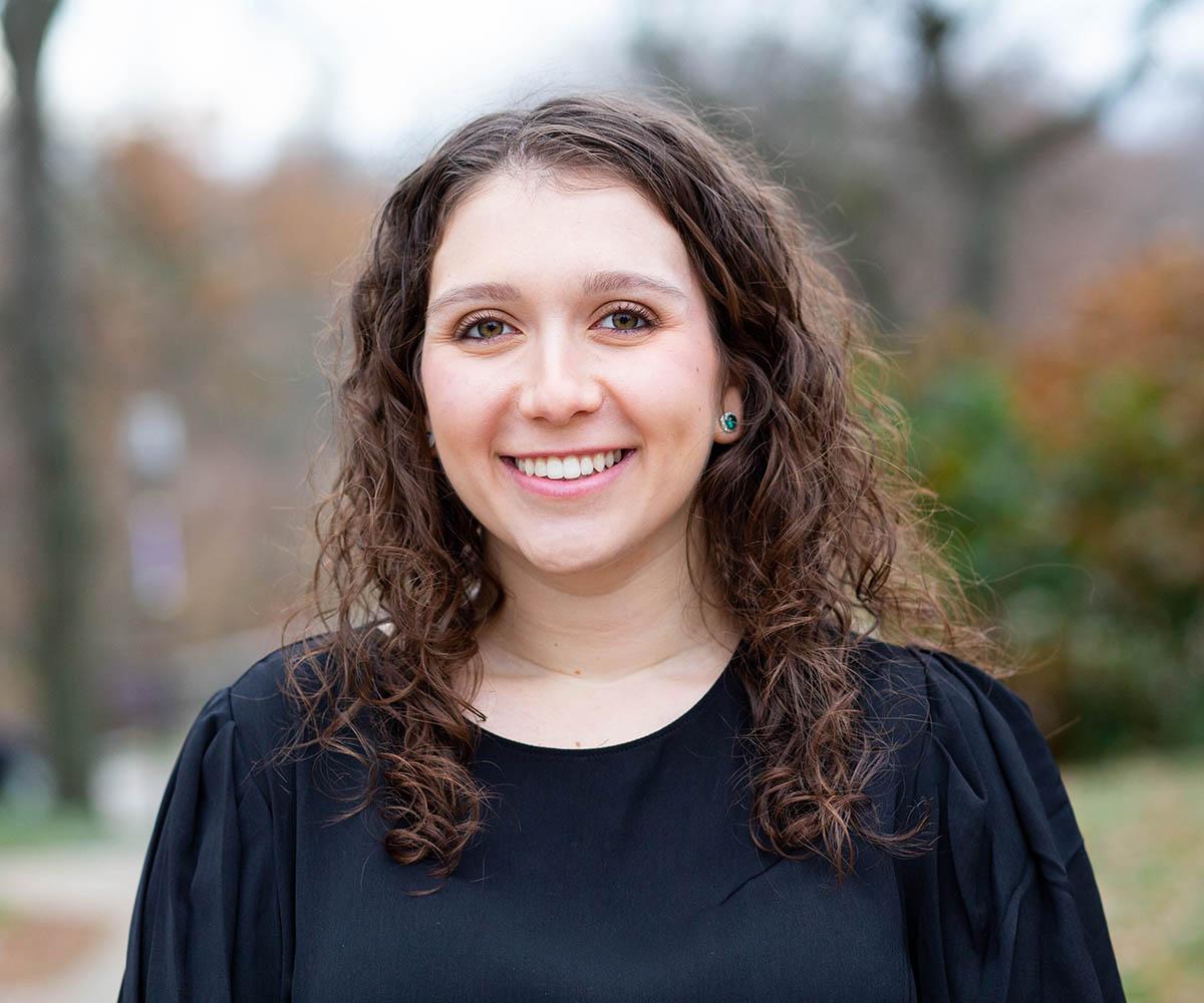 Photo of Leah, a smiling young woman with curly brown hair