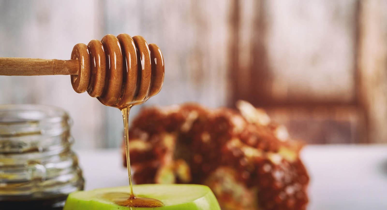 Photo of honey dripping from a wooden honey dipper